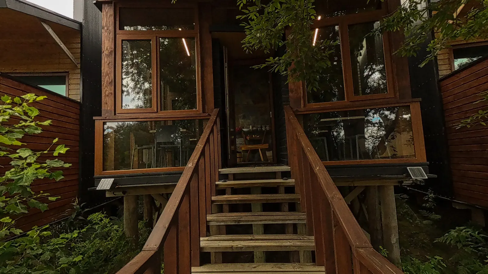 Escalera de madera hacia uno de los edificios de Ni-Newen Lodge, entre el bosque, en su recorrido virtual 360
