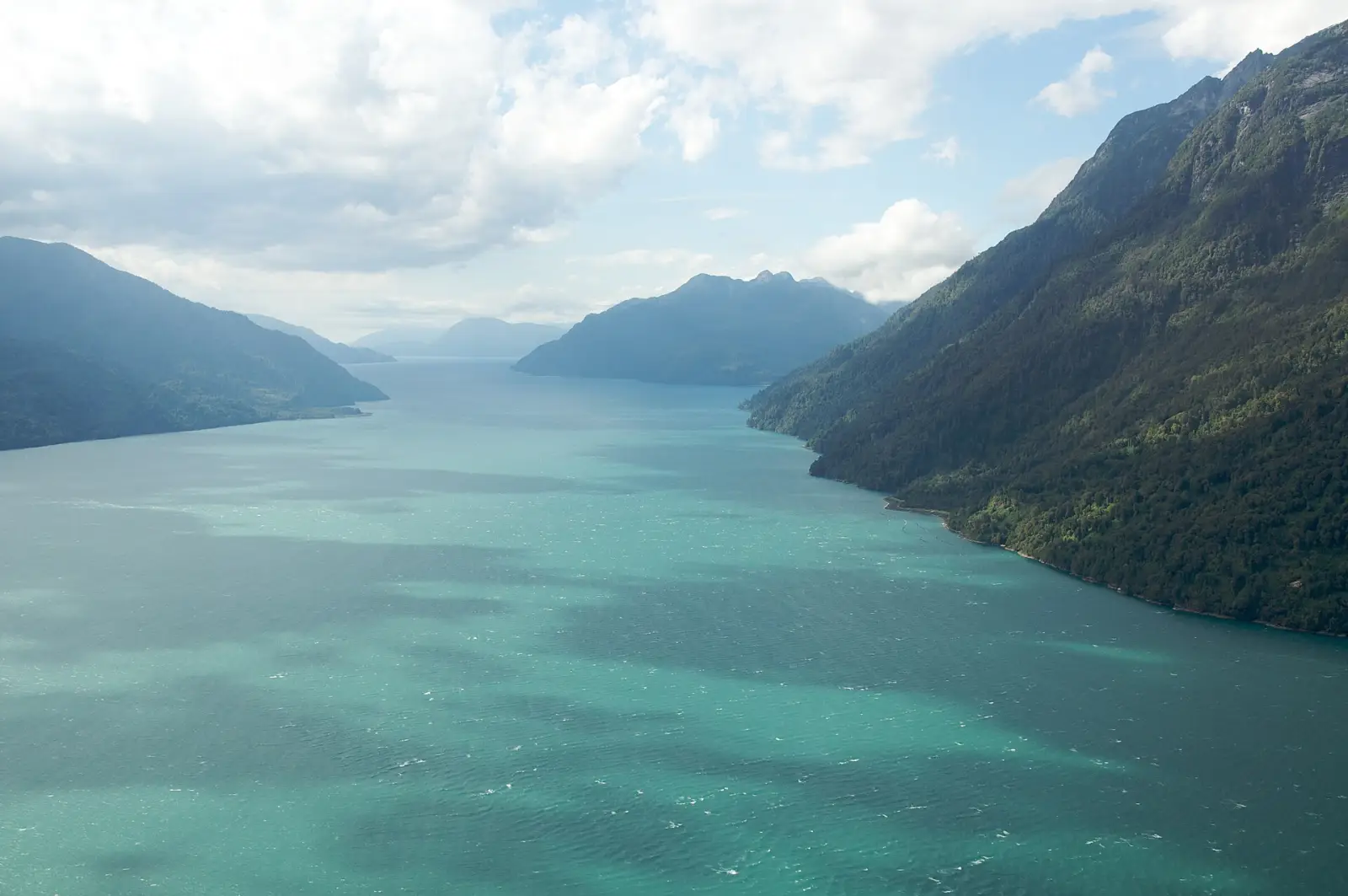 Vista aérea del fiordo Comau, en la Patagonia de Los Lagos, con aguas turquesa entre laderas de bosque nativo
