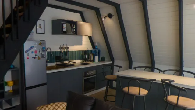 Recorrido virtual 360° de Tatai Sur Lodge en Malalcahuello: interior de una cabaña A-frame con cocina y barra
